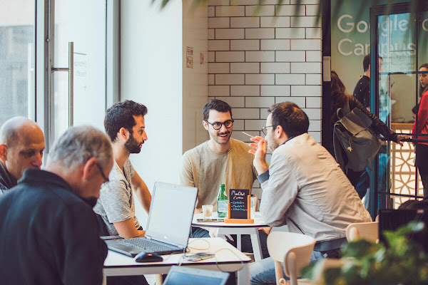 Three guys sitting at table discussing